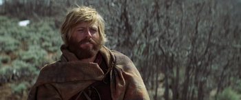 Movie still from “Jeremiah Johnson” (1972), directed by Sydney Pollack – A man with long hair and a beard is wrapped in a blanket; Close Up shot, Low angle