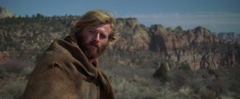 Movie still from “Jeremiah Johnson” (1972), directed by Sydney Pollack – A man with long hair and a beard standing in the desert; Close Up shot, Low angle
