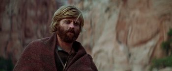 Movie still from “Jeremiah Johnson” (1972), directed by Sydney Pollack – A man with long hair and a beard is wearing a blanket; Close Up shot, Low angle