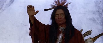 Movie still from “Jeremiah Johnson” (1972), directed by Sydney Pollack – A man in a native american costume holding a stick in his hand; Close Up shot, Low angle
