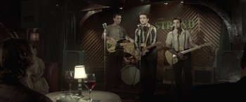 Movie still from “Jersey Boys” (2014), directed by Clint Eastwood – A group of men performing on stage in front of microphones; Medium shot, Over the shoulder angle