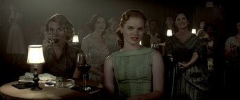 Movie still from “Jersey Boys” (2014), directed by Clint Eastwood – A woman sitting at a table in front of a group of people; Medium shot, Over the shoulder angle