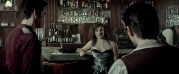 Movie still from “Jersey Boys” (2014), directed by Clint Eastwood – A beautiful woman in a black and silver dress; Medium shot, Over the shoulder angle