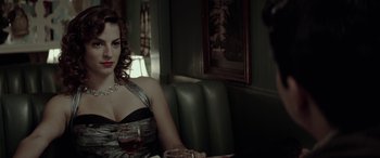 A woman sitting in a booth holding a glass of wine