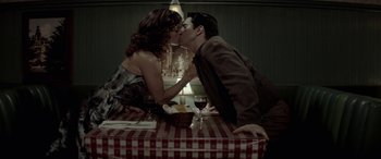 Movie still from “Jersey Boys” (2014), directed by Clint Eastwood – A man and a woman kissing at a table; Medium shot, Overhead angle