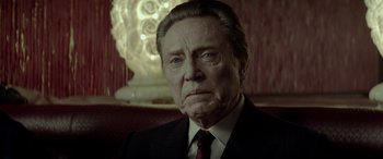 Movie still from “Jersey Boys” (2014), directed by Clint Eastwood – An older man wearing a suit and tie in front of a light fixture; Close Up shot, Low angle