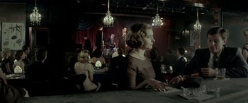 Movie still from “Jersey Boys” (2014), directed by Clint Eastwood – A woman sitting at a table in front of a microphone; Wide shot, Over the shoulder angle
