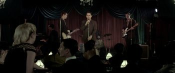 Movie still from “Jersey Boys” (2014), directed by Clint Eastwood – A group of men in suits singing at a party; Wide shot, High angle