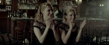 Movie still from “Jersey Boys” (2014), directed by Clint Eastwood – Two women in black dresses are clapping in a bar; Medium shot, Over the shoulder angle