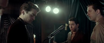 Movie still from “Jersey Boys” (2014), directed by Clint Eastwood – Two men are standing in front of microphones in front of lights; Medium shot, Low angle