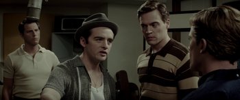 Movie still from “Jersey Boys” (2014), directed by Clint Eastwood – Two men standing next to each other in a room; Medium shot, Over the shoulder angle