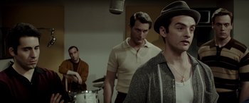 Movie still from “Jersey Boys” (2014), directed by Clint Eastwood – A group of men standing next to each other in a room; Medium shot, Over the shoulder angle