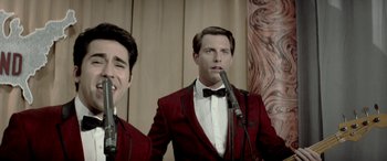 Movie still from “Jersey Boys” (2014), directed by Clint Eastwood – A man in a red jacket is singing into a microphone; Medium shot, Overhead angle