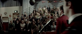 Movie still from “Jersey Boys” (2014), directed by Clint Eastwood – A crowd of people sitting in front of a microphone; Wide shot, High angle