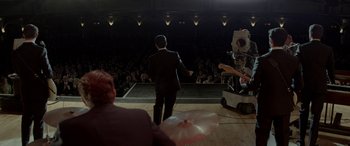 Movie still from “Jersey Boys” (2014), directed by Clint Eastwood – A man standing on a stage in front of an audience; Wide shot, High angle