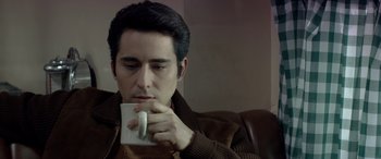 Movie still from “Jersey Boys” (2014), directed by Clint Eastwood – A man sitting on top of a couch holding a coffee mug; Close Up shot, High angle