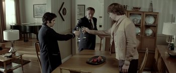 Movie still from “Jersey Boys” (2014), directed by Clint Eastwood – Three people are toasting with wine at a dinner table; Medium shot, Over the shoulder angle