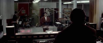 Movie still from “Jersey Boys” (2014), directed by Clint Eastwood – A man is standing in front of a microphone in a recording studio; Medium shot, Over the shoulder angle