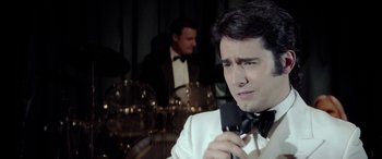 Movie still from “Jersey Boys” (2014), directed by Clint Eastwood – A man holding a microphone in front of another man; Close Up shot, Over the shoulder angle