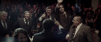 Movie still from “Jersey Boys” (2014), directed by Clint Eastwood – A group of men in suits raising their hands in the air; Medium shot, High angle