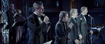 Movie still from “Jersey Boys” (2014), directed by Clint Eastwood – A group of men in tuxedos sing into microphones; Medium shot, Low angle