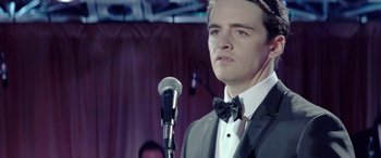 Movie still from “Jersey Boys” (2014), directed by Clint Eastwood – A man wearing a bow tie standing in front of a microphone; Close Up shot, Over the shoulder angle