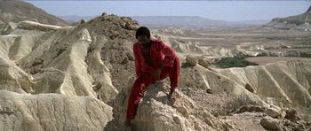 Movie still from “Jesus Christ Superstar” (1973), directed by Norman Jewison – A man in a red suit climbing a rock; Wide shot, Low angle