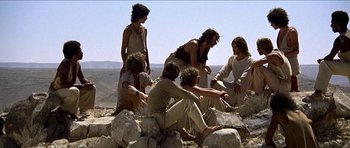 Movie still from “Jesus Christ Superstar” (1973), directed by Norman Jewison – A group of people sitting on top of a rock; Wide shot, Low angle