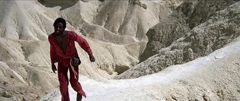 Movie still from “Jesus Christ Superstar” (1973), directed by Norman Jewison – A man in a red suit is snowboarding down a mountain; Extreme Wide shot, High angle