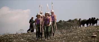 Movie still from “Jesus Christ Superstar” (1973), directed by Norman Jewison – A group of men in purple shirts and white hats holding wooden spears; Wide shot, Low angle