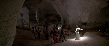 Movie still from “Jesus Christ Superstar” (1973), directed by Norman Jewison – A group of people standing around in a cave; Extreme Wide shot, High angle