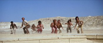 Movie still from “Jesus Christ Superstar” (1973), directed by Norman Jewison – A group of people in the sand on a beach; Wide shot, Low angle