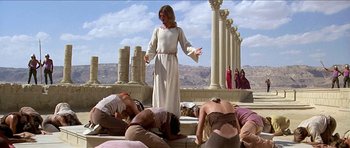 Movie still from “Jesus Christ Superstar” (1973), directed by Norman Jewison – A woman in a white robe standing in front of a group of people; Wide shot, Low angle