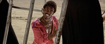 Movie still from “Jesus Christ Superstar” (1973), directed by Norman Jewison – A man in a pink shirt is standing in the dirt; Medium shot, Low angle