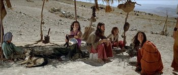 Movie still from “Jesus Christ Superstar” (1973), directed by Norman Jewison – A group of people sitting on the ground under an awning; Wide shot, Low angle