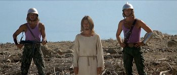 Movie still from “Jesus Christ Superstar” (1973), directed by Norman Jewison – A man standing in the middle of a field with another man standing next to him; Medium shot, Low angle