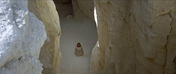 Movie still from “Jesus Christ Superstar” (1973), directed by Norman Jewison – A woman in a white dress standing in the middle of a cave; Extreme Wide shot, High angle