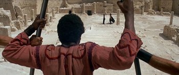 Movie still from “Jesus Christ Superstar” (1973), directed by Norman Jewison – A man standing in front of an ancient building; Extreme Wide shot, Over the shoulder angle