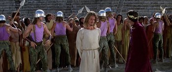 Movie still from “Jesus Christ Superstar” (1973), directed by Norman Jewison – A group of men in purple shirts and one man in a white shirt; Medium shot, Over the shoulder angle