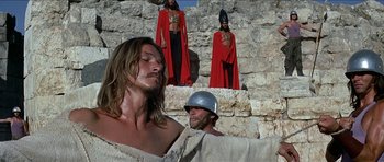 Movie still from “Jesus Christ Superstar” (1973), directed by Norman Jewison – A group of people standing next to each other on some rocks; Medium shot, Low angle