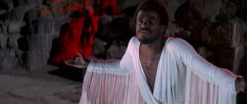 Movie still from “Jesus Christ Superstar” (1973), directed by Norman Jewison – A man in a white robe is holding his hand out; Medium shot, Low angle