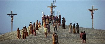 Movie still from “Jesus Christ Superstar” (1973), directed by Norman Jewison – A group of people standing around a cross on a hill; Extreme Wide shot, Low angle
