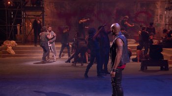 Movie still from “Jesus Christ Superstar Live in Concert” (2018), directed by Alex Rudzinski – A group of people dancing on a stage; Wide shot, Over the shoulder angle