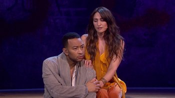 Movie still from “Jesus Christ Superstar Live in Concert” (2018), directed by Alex Rudzinski – A man and a woman are sitting on a stage; Medium shot, High angle