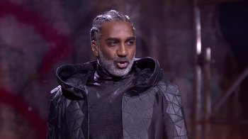 Movie still from “Jesus Christ Superstar Live in Concert” (2018), directed by Alex Rudzinski – A man with a gray beard wearing a black jacket; Medium shot, Low angle