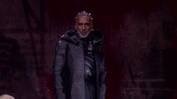 Movie still from “Jesus Christ Superstar Live in Concert” (2018), directed by Alex Rudzinski – An older man wearing a black and silver jacket; Medium shot, Low angle