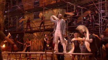 Movie still from “Jesus Christ Superstar Live in Concert” (2018), directed by Alex Rudzinski – A group of people standing on top of a stage; Wide shot, Low angle
