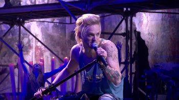 Movie still from “Jesus Christ Superstar Live in Concert” (2018), directed by Alex Rudzinski – A person with a microphone on a stage; Medium shot, Over the shoulder angle