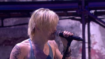 Movie still from “Jesus Christ Superstar Live in Concert” (2018), directed by Alex Rudzinski – A man with blonde hair is singing into a microphone; Close Up shot, High angle