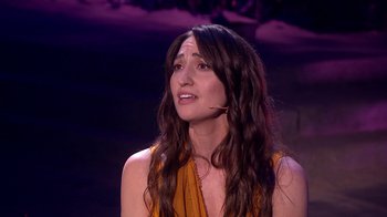 Movie still from “Jesus Christ Superstar Live in Concert” (2018), directed by Alex Rudzinski – A woman with long brown wavy hair wearing an orange top; Close Up shot, High angle